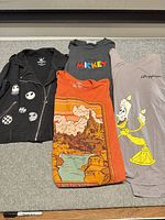 All four clothing items laid out: jacket, two T-shirts, bodysuit