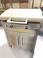 Front view of Blackstone stainless steel griddle grill with two knobs and storage cabinet