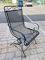 Front angled view of black wrought iron mesh rocking chair on spring base