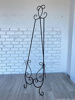 Full view of black metal scrollwork floor easel