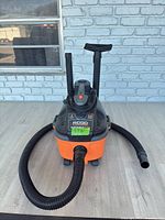 Front view of Ridgid portable wet/dry vacuum with hose and extension wands attached