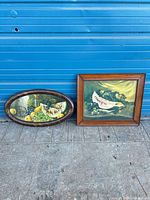 Both framed prints leaning against blue wall