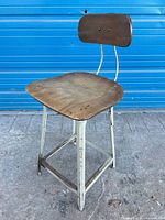Three-quarter view of entire stool showing steel frame, wood seat and backrest