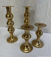 All four brass candlestick holders, two heights visible