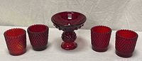 Front view of all five ruby red hobnail pieces in a row