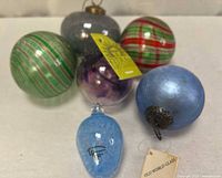 Group of six blown glass ornaments showing colors, patterns, tags