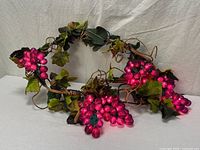 Garland illuminated showing pink-purple lit grape clusters, foliage, vine form