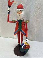 Full view of hand-painted metal Santa figurine standing on round base