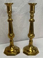 Front view of both brass candlesticks showing turned columns and octagonal bases