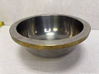 Side view showing pewter body, brass rim, and foot ring
