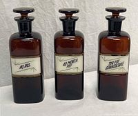Front view of all three amber apothecary bottles showing labels and stoppers
