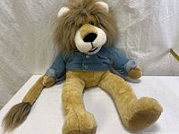 Full view of plush lion hand puppet wearing denim jacket