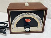 Front view showing mahogany case, black dial, semicircular scale, pointer knob, brand badge