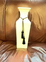 Front view of white square column vase with black tassel cord
