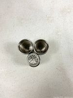 Top view of three stainless steel shot glasses showing interiors and embossed bases