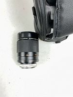 Spiratone mirror lens positioned beside storage bag on white surface