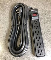 Full view of black 6-outlet power bar and coiled cord