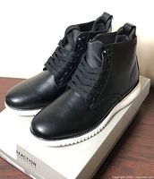 pair of black Kenneth Cole Reaction Tech Boots on top of original box