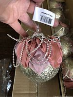 Close-up of single ornament showing glitter surface, fabric petals, bead loops