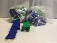 Bundles of green and blue tie-down straps in plastic bags