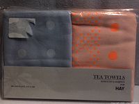 Front of sealed package showing two folded tea towels, brand and designer