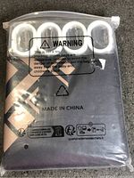 Front of packaged shower curtain showing pattern, warning text, hooks visible