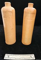 Front view of both stoneware bottles with ruler for scale