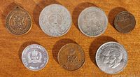 All seven medals and coins obverse sides on wood surface