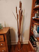 Full view of carved wooden cattail sculpture beside furniture for scale
