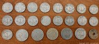 Obverse sides of 25 French aluminum coins laid out on wood surface