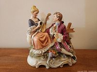 Front view of porcelain figurine showing couple, instruments, base details
