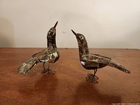 Two abalone shell bird figurines on table