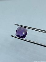Front angle of cushion checkerboard amethyst held by tweezers