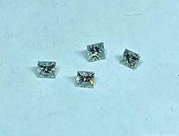 Four loose princess cut diamonds on plain background