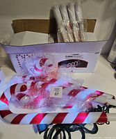 Box containing four wrapped candy cane pathway lights with power cords