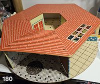 overall view of hexagonal tin dollhouse showing roof, round base on wheels