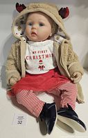 Front view of reborn doll seated, shows facial details and full Christmas outfit