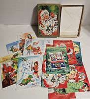 Box lid with Santa illustration and spread of vintage Christmas cards around it