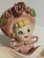 Front view showing hand-painted face, bonnet, roses