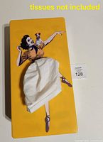 Top view of yellow tissue box cover with tissue protruding through skirt opening