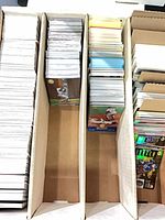 Three long storage box rows containing stacks of trading cards, some in plastic sleeves