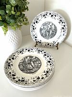 Front view of five stacked plates and one displayed showing decoration