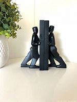 Front view of both leaning man bookends supporting books
