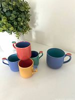 All five mugs stacked showing colors and thumb rests