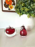 Apple and pear glass paperweights on surface