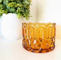Front view of amber glass planter next to white pot showing pattern and color