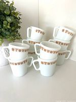 Ten Pyrex Butterfly Gold mugs stacked