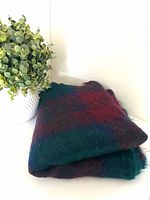 Folded plaid mohair blanket beside plant