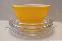 Yellow Pyrex mixing bowl stacked on clear lids