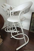 Four white Amisco bar stools stacked